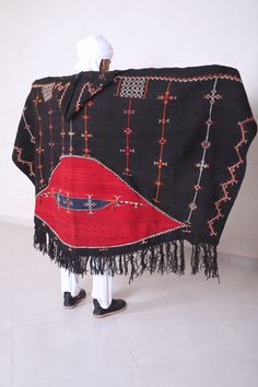 "Authentic moroccan black cape Please see last images for more details on the dimensions 229 CM X 111 CM = 90.1 INCHES X 43.7 INCHES Akhnif is the name for the shepherd's cloak as it was worn in south western morocco by jewish and berber men and boys. The akhnif cape was woven in one piece on an upright loom. from goat's hair or wool. Typical for this black mens burnous is bright red \" half moon \" on the back. visible from great distance, The richly embroidered decoration made an akhnif of thi Traditional Long Sleeve Poncho, Traditional Black Shawl Outerwear, Traditional Black Cape For Festival, Traditional Black Festival Cape, Traditional Black Ceremonial Outerwear, Traditional Shawl Outerwear, Berber Clothing, Embroidered Decoration, Mens Cape