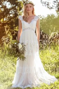 a woman in a wedding dress standing in the grass