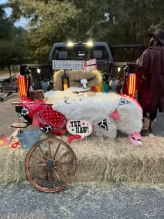 a large stuffed animal sitting on top of hay next to a wagon filled with stuff