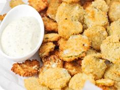 a white plate topped with fried food next to a bowl of ranch dressing