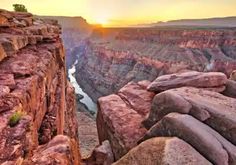 the sun is setting at the edge of an overlook point in grand canyon national park