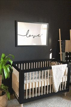 a baby's room with black walls, white crib and potted plants