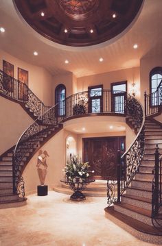 a large foyer with stairs and potted plants on the table in front of it