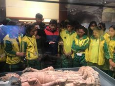 a group of people looking at a statue in a glass case while others look on