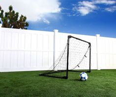 a soccer ball sitting on top of a green field next to a goalie net