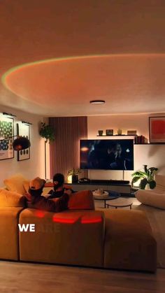 a man sitting on top of a couch in front of a tv mounted to the wall