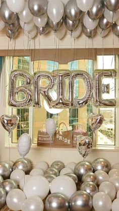 balloons are hanging from the ceiling in front of a window with bride's sign