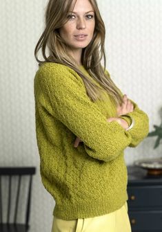 a woman standing with her arms crossed wearing a green sweater