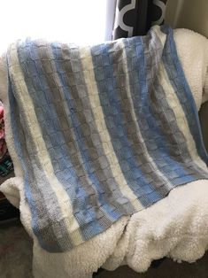 a blue and white blanket sitting on top of a couch