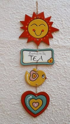 three wooden signs hanging from the side of a wall with hearts and sun on them