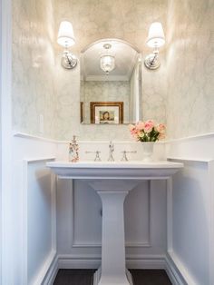 a white pedestal sink sitting under a bathroom mirror