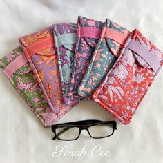 five different colored napkins with glasses on the top one is folded and has pink ribbon around it