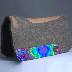 a gray felt purse with multicolored designs on the front and bottom, sitting on a white surface