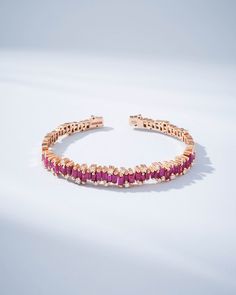 The Shimmer Audrey Ruby Bangle is the epitome of sophistication and refined style. It is exquisitely handcrafted with 18-karat spring gold wire to ensure both comfort and flexibility. Set with 4.00 carats of striking ruby baguettes and accented with 0.42 carats of glistening round white diamonds, this bangle makes a profound statement of luxury. Whether it graces your wrist alone or is paired with other bracelets, its beauty is guaranteed to elevate your look. Details 18k rose gold 4.00 carats o Elegant Ruby Bangle Jewelry, Festive Ruby Round Bangle, Fine Jewelry Ruby Bangle, Ceremonial Ruby Bangle Jewelry, Luxury Red Ruby Bangle, Ruby Bangles, Bangles Making, Refined Style, Gold Wire