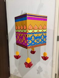 a colorful paper lantern hanging from a hook on a door way with red and yellow decorations