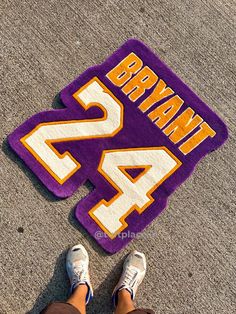 a person standing next to a purple and yellow mat with the number 24 on it