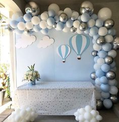 a table with some balloons on it and a white table cloth under the balloon arch