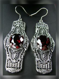 Red Garnet Solid Sterling Silver Earrings Oval Castle Design#E4 Inspired by the Art Deco movement of the early 1900s, this is a pair of Art Deco antique reproduction earrings in sterling silver. The flawless red garnet gems are surrounded by delicate sterling silver filigree. The lovely 7.54 carat oval stones are approximately 14mm by 10mm in length & width. The gemstones have excellent color and clarity. The earrings are 2-1/2" long and are marked 925 for sterling silver. These elegant earrings Ornate Red Drop Earrings, Elegant Ruby Earrings Nickel-free, Elegant Ruby Earrings Nickel Free, Elegant Red Nickel-free Crystal Earrings, Elegant Red Crystal Earrings Nickel Free, Ornate Red Earrings For Formal Occasions, Red Gemstone Earrings For Gift, Red Jeweled Earrings For Gift, Red Oval Earrings For Formal Occasions