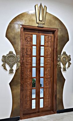 a large wooden door in front of a white wall