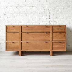 a large wooden dresser sitting on top of a hard wood floor next to a white brick wall