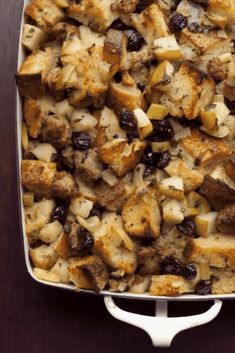 a casserole dish filled with stuffing and vegetables on a wooden table, ready to be eaten