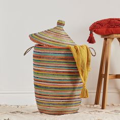 a multicolored basket sitting on the floor next to a stool