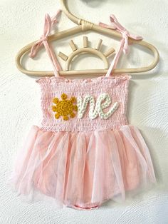 Our custom hand embroidered name tutus are sure to look adorable on the sweet little one in your life!  Give them as gifts for baby showers, name announcements, first birthday's, Xmas gifts, and more!  These tutu's are also perfect to wear for your little one's first birthday!  Just pick out the color tutu and yarn you want and leave the rest up to us!  Your little girl will look absolutely adorable in her StitchedxStacey custom tutu! Choose the color of your tutu romper in the above drop down. Cute Floral Applique Dress For Birthday, Whimsical Summer Tutu Dress For First Birthday, Whimsical Summer Tutu Dress For Playtime, Birthday Tutu Dress With Floral Applique, Summer Baptism Tutu Dress With Floral Applique, Princess Tutu Dress With Floral Applique For Birthday, Princess Style Tutu Dress With Floral Applique For Birthday, Cute Tutu Dress For Baptism In Summer, Whimsical Summer Tutu Dress For Cake Smash