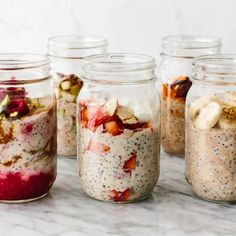 four jars filled with different types of food on top of a marble countertop next to each other