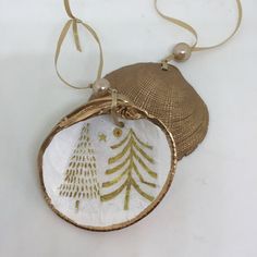 an ornament with a christmas tree on it is hanging from a gold ribbon