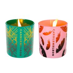 two candles are sitting next to each other on a white background, one is green and the other is pink