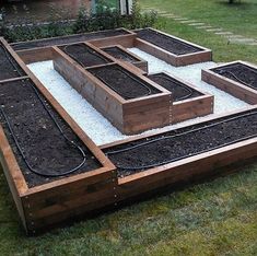 a raised garden bed with plants and gravel in the middle, on top of grass