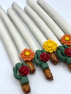 four white candles with flowers on them sitting next to each other in the shape of sticks