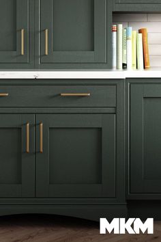 a kitchen with green cabinets and white counter tops, along with bookshelves on the wall