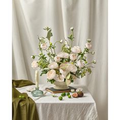 a white table topped with a vase filled with lots of flowers next to a candle