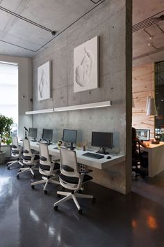 there are many computers on the desks in this large office space with windows looking out onto the city