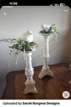 two white vases sitting on top of a table next to each other with flowers in them