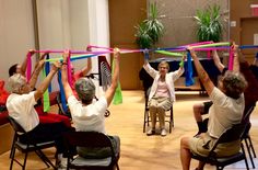 people holding up ribbons in the air while sitting on chairs with their hands behind them