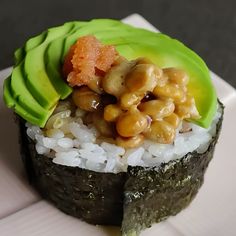 a sushi with rice, beans and avocado is on a white plate