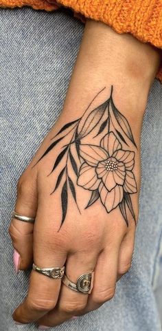 a woman's hand with a flower tattoo on it