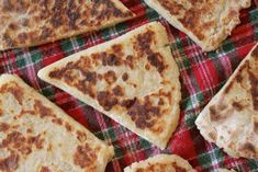 several flatbread pizzas on a red and green checkered cloth