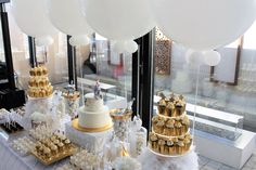 a table topped with lots of cakes and cupcakes covered in white frosting