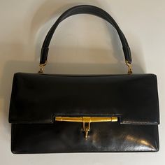 Hermes Palonnier Handbag In A Smooth Black Leather. Leather Shows Scratches And Corner Wear Consistent With Older Bag. Single Flat Top Handle With 5.5 Inch Drop. Creasing On Handle Leather. Dark Gold Tone Hardware With Tarnish. Front Top Flap With Hook Clasp Closure. Leather Lined Interior With Four Compartments - A Large Gusset Pocket, A Rear Slip Pocket Behind A Snap Closure Pouch And A Front Slip Pocket. Gold Embossed Hermes Paris Stamp. No Box Or Dust Bag. An Oldie But A Goodie In A Vintage Paris Stamp, Hermes Clutch, Hermes Paris, Dark Gold, Hook Clasp, Hermes Bags, Pocket Book, Flats Top, Snap Closure