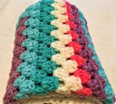 a multicolored crocheted blanket on top of a white table