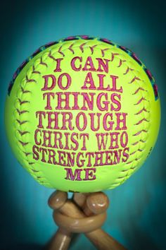 a yellow baseball with pink lettering on it sitting on a wooden stand in front of a blue background