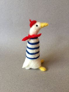 a small toy chicken with a red scarf around its neck on a gray surface,