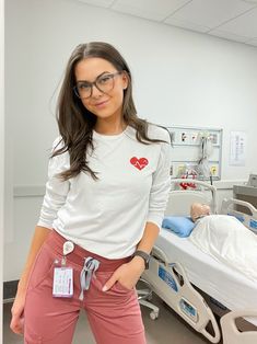 a woman standing in a hospital room with her hand on her hip and looking at the camera