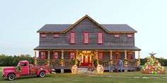 a red truck parked in front of a house with christmas decorations on the porch and windows