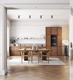 an open kitchen and dining room with wood flooring, white walls and wooden cabinets