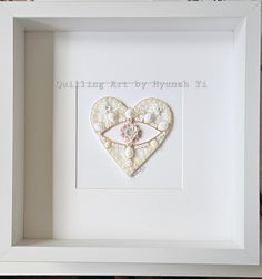 a white frame with a heart shaped brooch in it