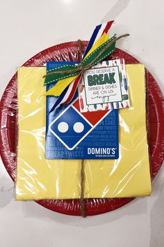 a red plate topped with two pieces of cake next to a piece of paper that says break domino's